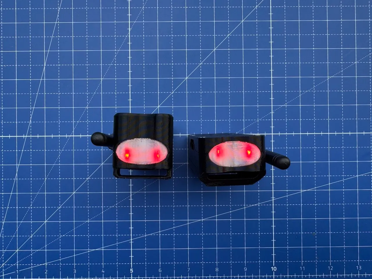 Two enclosures viewed head-on, the oval LED window lit red