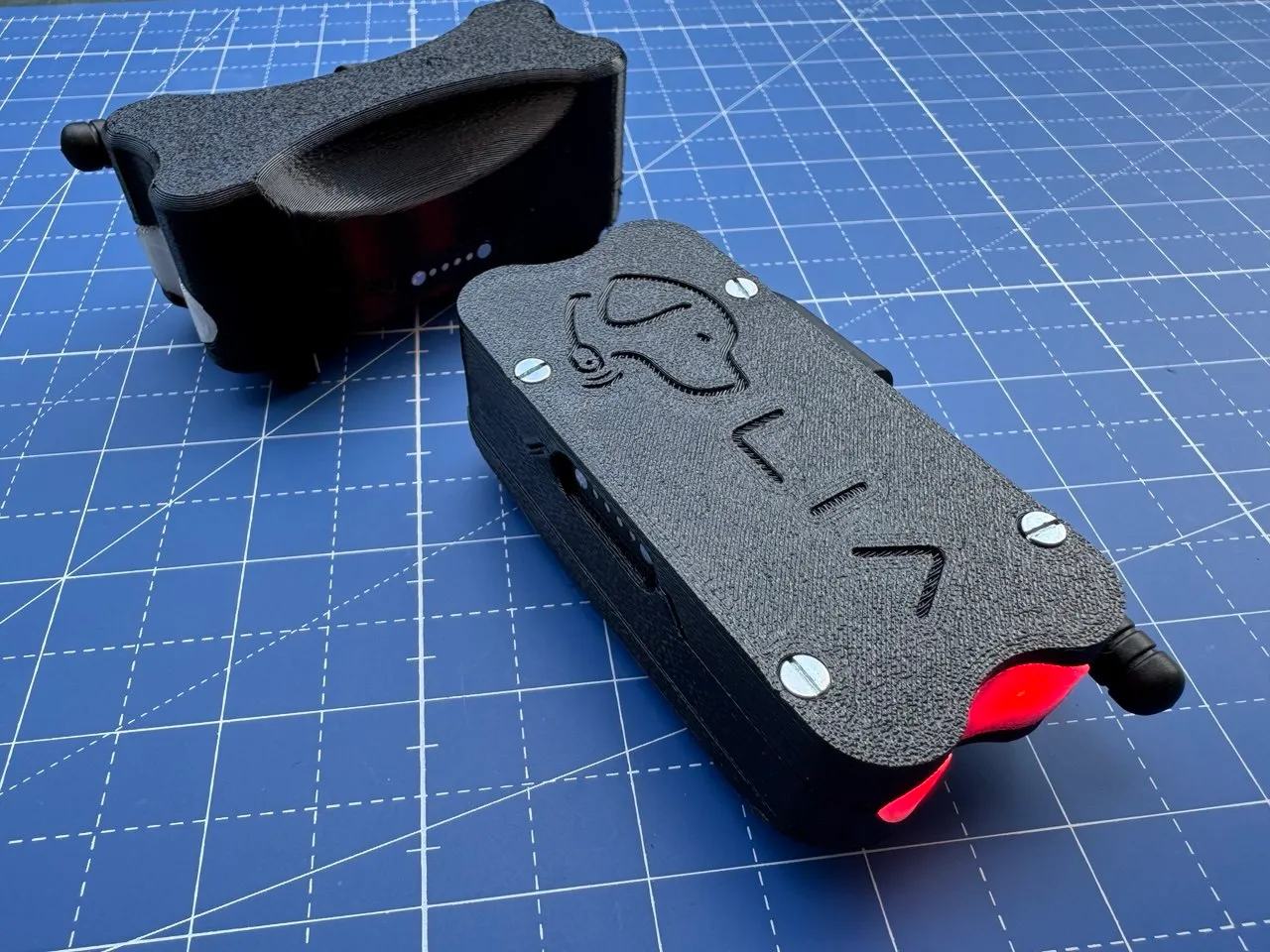 Detachable collar clip and assembled enclosure, status LED glowing red, close-up